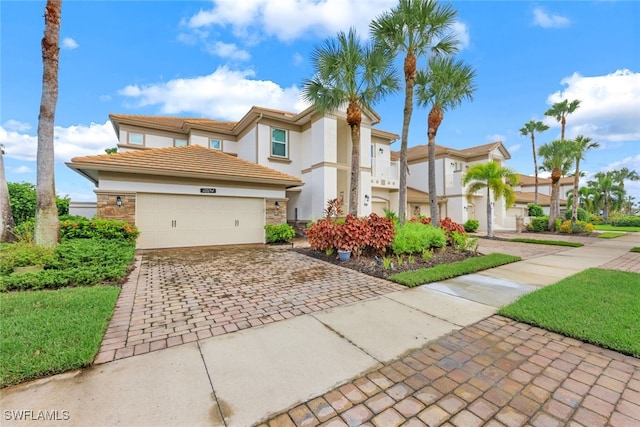 view of front of home with stucco siding, decorative driveway, stone siding, a garage, and a tiled roof