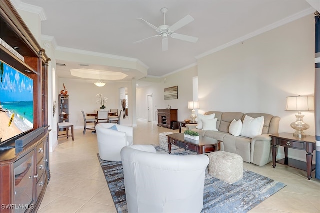 living area with light tile patterned floors, a tray ceiling, ornamental molding, and a ceiling fan