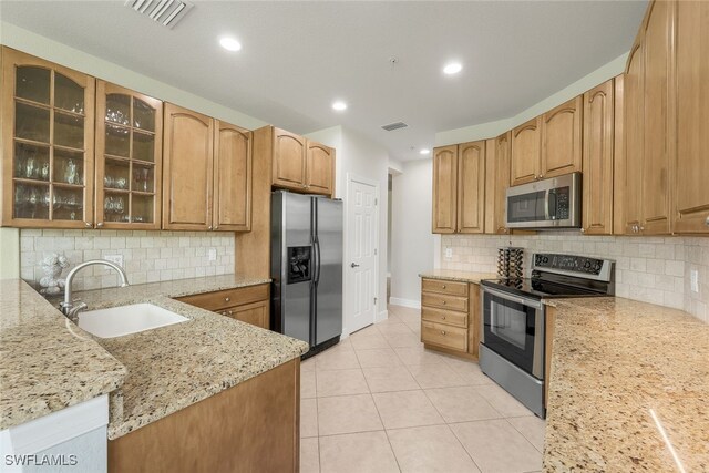 kitchen featuring visible vents, light stone countertops, light tile patterned flooring, stainless steel appliances, and a sink