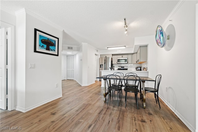 dining space with crown molding, a textured ceiling, and hardwood / wood-style flooring