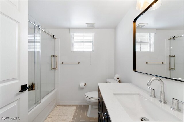 full bathroom with shower / bath combination with glass door, vanity, toilet, and plenty of natural light