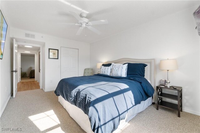 bedroom with light colored carpet, ceiling fan, and a closet