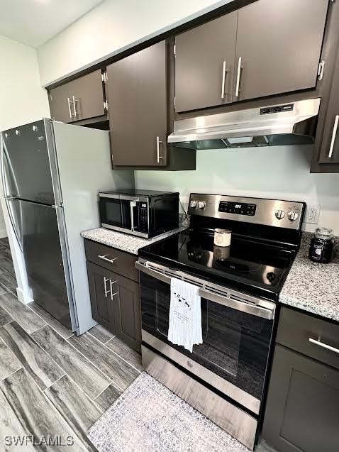 kitchen with light stone countertops, stainless steel appliances, and light hardwood / wood-style flooring