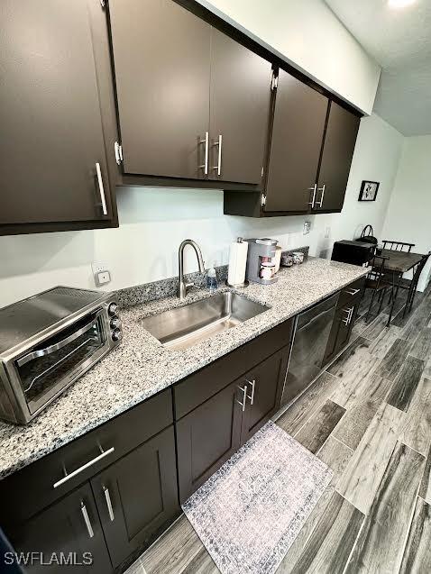 kitchen with dark brown cabinets, light wood-type flooring, and sink