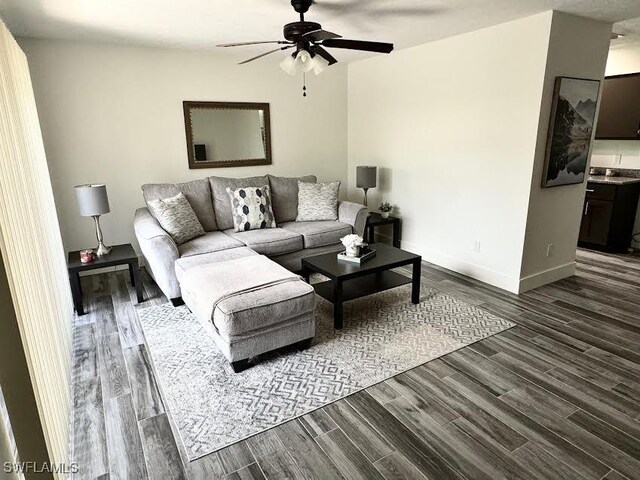 living room featuring ceiling fan and dark wood-type flooring