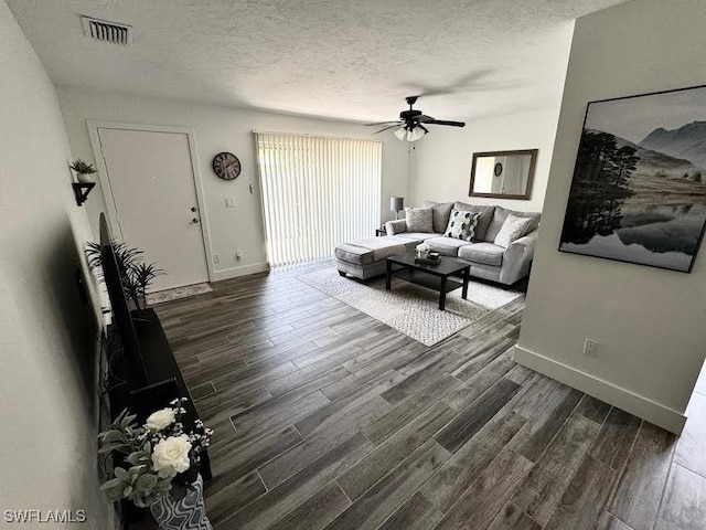 living room with ceiling fan, dark wood-type flooring, and a textured ceiling