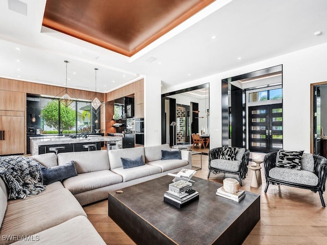 living room with a raised ceiling, plenty of natural light, and light hardwood / wood-style floors