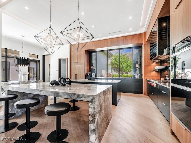 kitchen featuring pendant lighting, a kitchen breakfast bar, a large island, a chandelier, and light stone counters