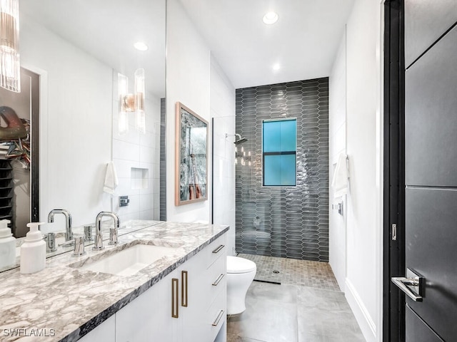 bathroom with toilet, vanity, and a tile shower