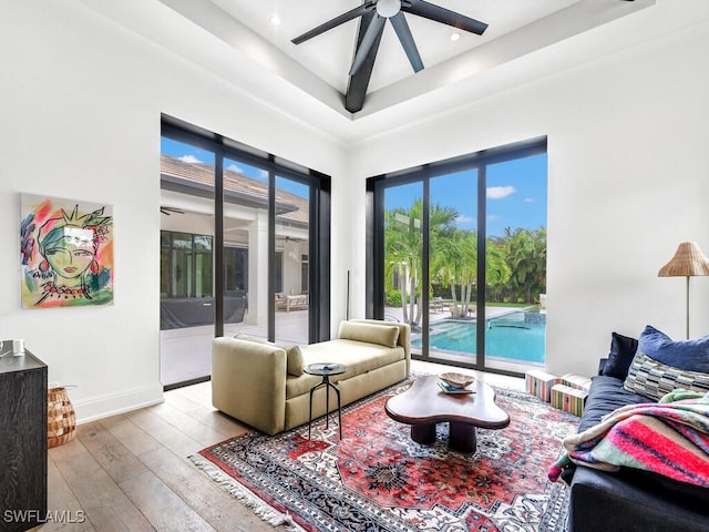 living room with ceiling fan, light hardwood / wood-style floors, and a high ceiling