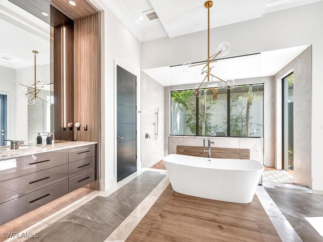 bathroom with a bathing tub, a healthy amount of sunlight, vanity, and a notable chandelier