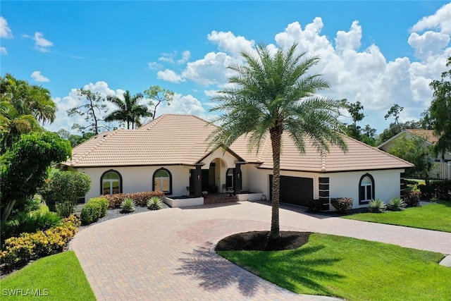 mediterranean / spanish-style house with a garage and a front lawn