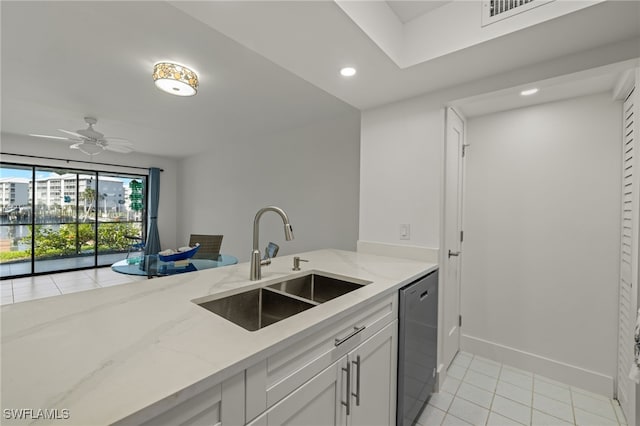 kitchen with light tile patterned floors, light stone counters, sink, ceiling fan, and stainless steel dishwasher