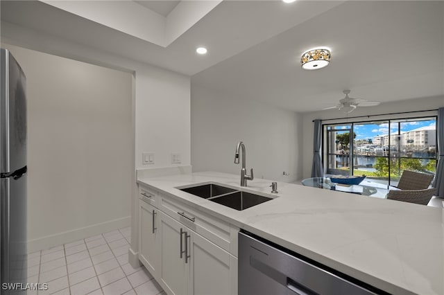 kitchen with white cabinets, appliances with stainless steel finishes, light stone countertops, sink, and ceiling fan