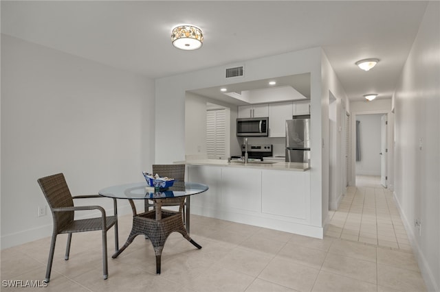 tiled dining area with a raised ceiling and sink