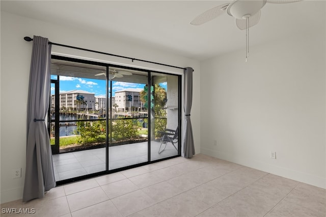 unfurnished room with a water view, ceiling fan, and light tile patterned floors