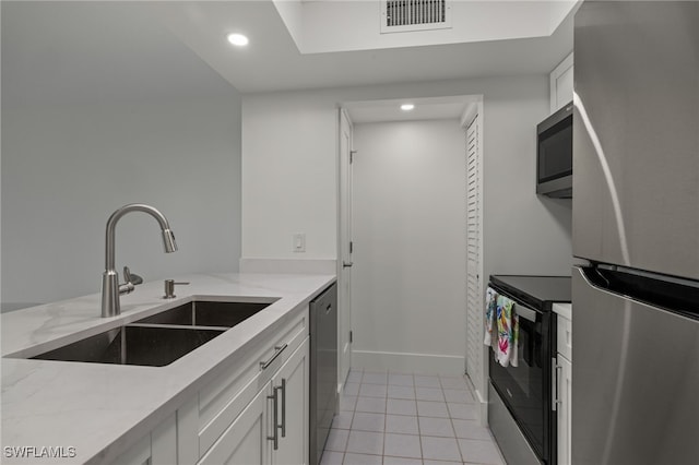 kitchen featuring light stone countertops, stainless steel appliances, white cabinetry, and sink