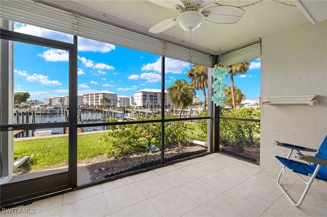 unfurnished sunroom featuring plenty of natural light, ceiling fan, and a water view