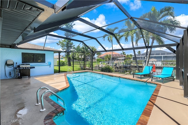 view of pool with glass enclosure, a patio, and grilling area