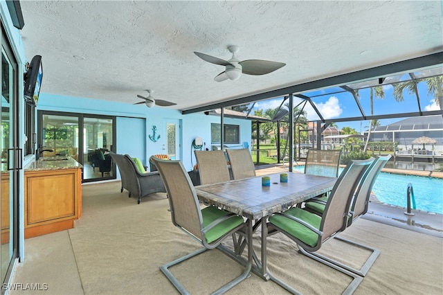 view of patio with ceiling fan, sink, and glass enclosure