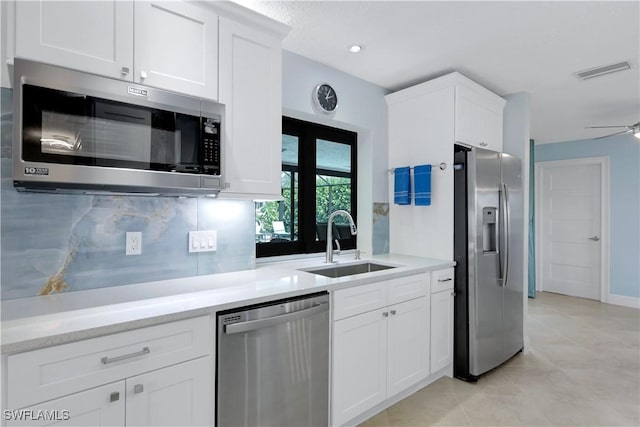 kitchen with backsplash, sink, ceiling fan, appliances with stainless steel finishes, and white cabinetry