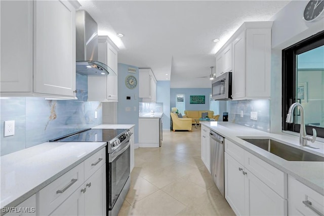 kitchen featuring white cabinetry, sink, stainless steel appliances, wall chimney range hood, and tasteful backsplash