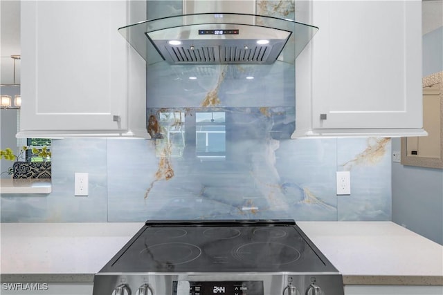 kitchen with stove, backsplash, white cabinets, and island exhaust hood