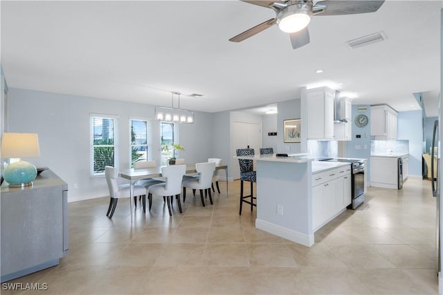 kitchen with stainless steel range with electric stovetop, pendant lighting, a center island, ceiling fan, and white cabinetry