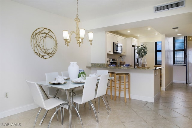 tiled dining room with sink and a notable chandelier