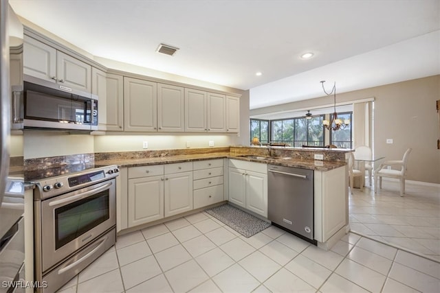 kitchen with sink, stainless steel appliances, kitchen peninsula, dark stone counters, and light tile patterned flooring