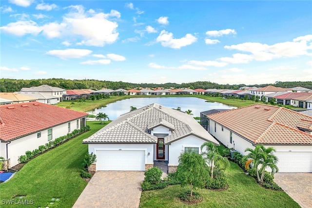 view of front of home with a front yard, a garage, and a water view