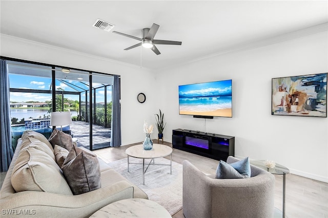 living room featuring light wood-type flooring, ceiling fan, a water view, and ornamental molding