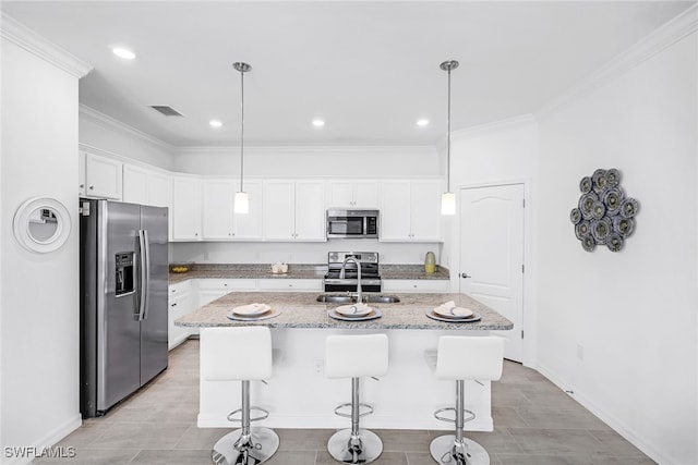 kitchen featuring appliances with stainless steel finishes, an island with sink, decorative light fixtures, and sink