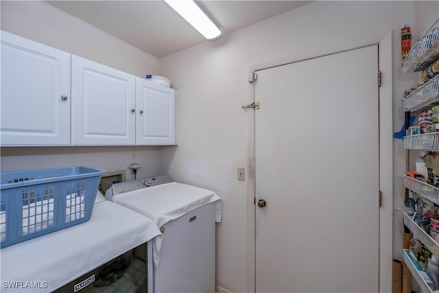 clothes washing area featuring cabinets and washer and clothes dryer