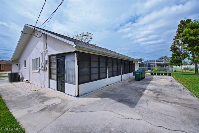 view of side of property with central air condition unit, a sunroom, and glass enclosure