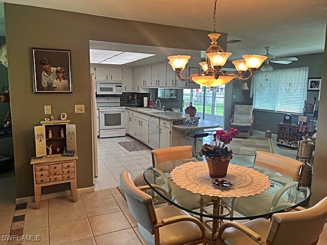 dining space featuring ceiling fan with notable chandelier, light tile patterned floors, and sink