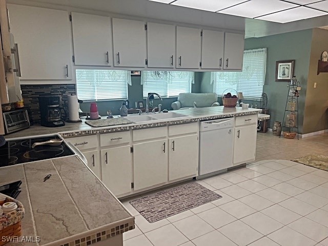 kitchen with dishwasher, light tile patterned flooring, sink, and white cabinets