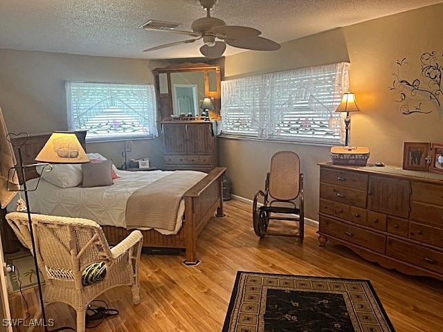 bedroom featuring ceiling fan, light hardwood / wood-style floors, and a textured ceiling