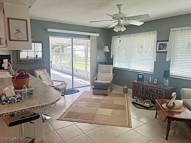 living room featuring a textured ceiling, plenty of natural light, ceiling fan, and light tile patterned floors