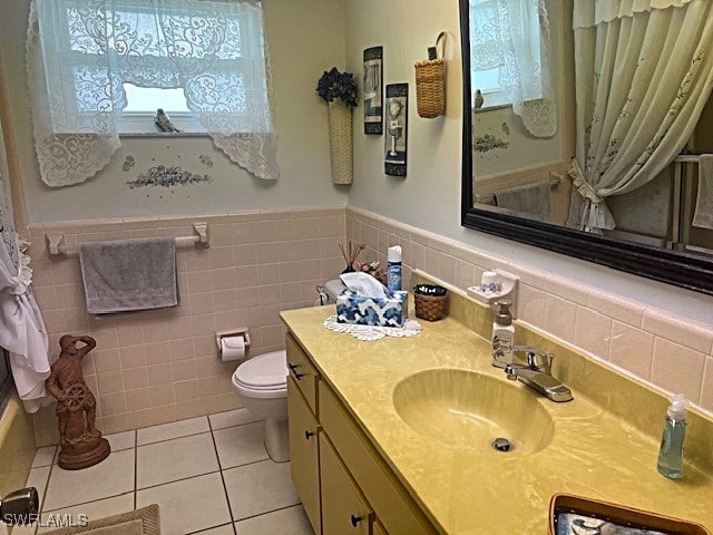 bathroom with toilet, tile patterned floors, vanity, tasteful backsplash, and tile walls