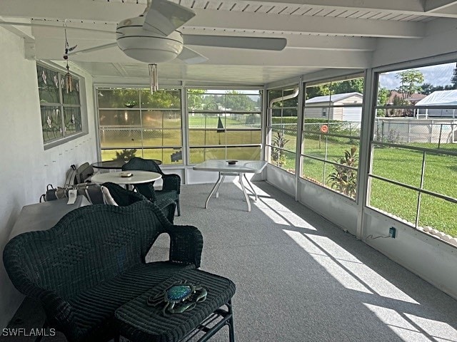 sunroom with ceiling fan, a wealth of natural light, and beam ceiling