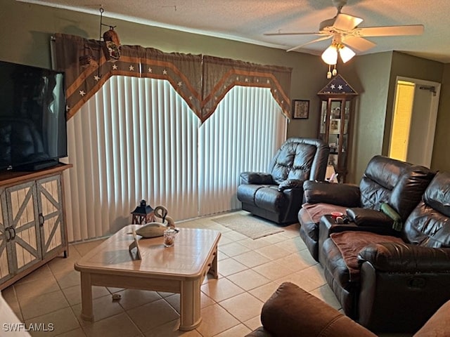 living room featuring ceiling fan, light tile patterned floors, and a textured ceiling