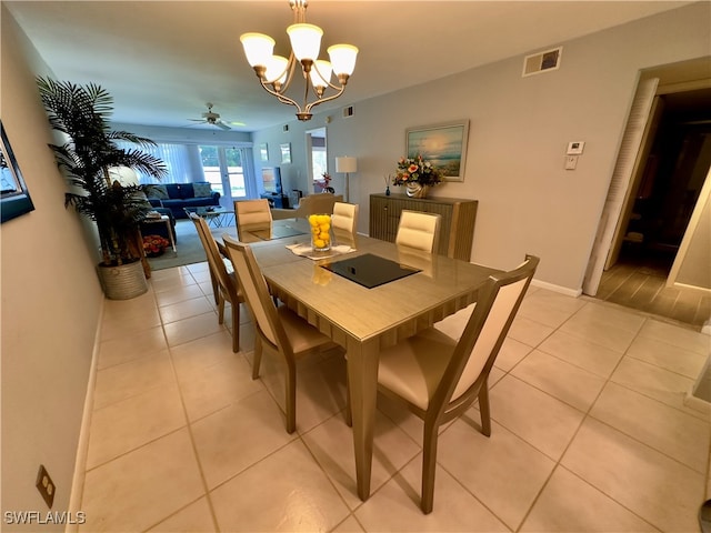 dining space with light tile patterned floors and ceiling fan with notable chandelier