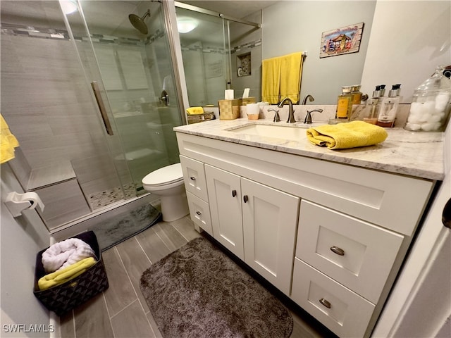 bathroom with vanity, toilet, and a shower with door