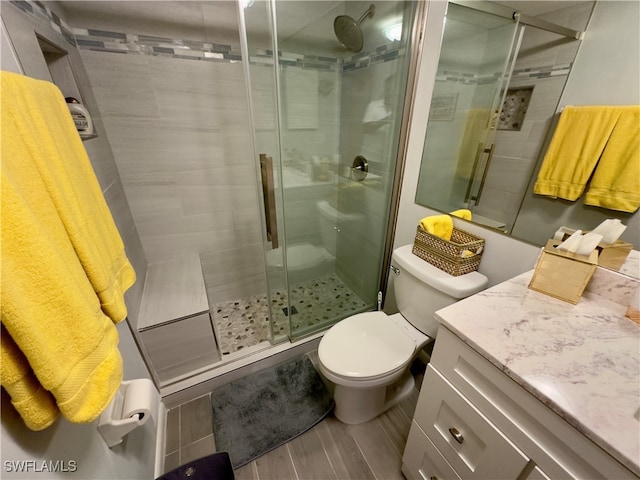 bathroom featuring vanity, hardwood / wood-style flooring, toilet, and a shower with door