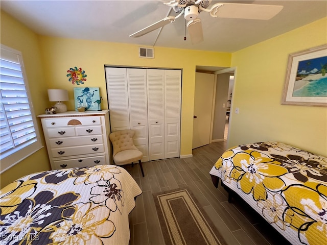 bedroom featuring multiple windows, ceiling fan, a closet, and dark wood-type flooring