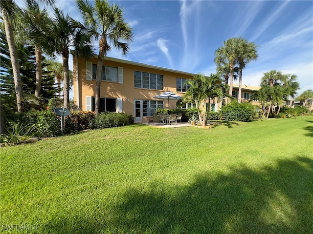 back of property featuring a lawn and a patio