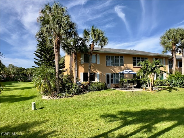 back of house featuring a lawn and a patio area