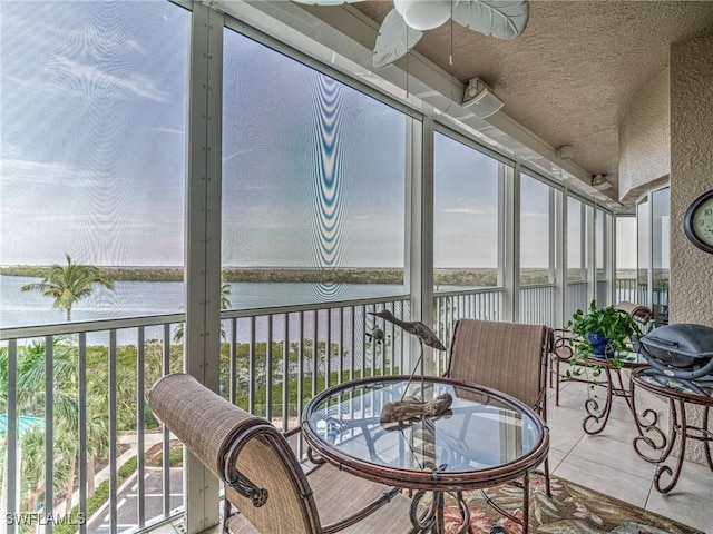 sunroom featuring a water view and ceiling fan