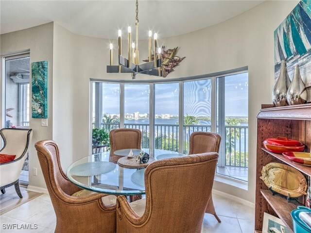 tiled dining area featuring a water view, a notable chandelier, and a wealth of natural light